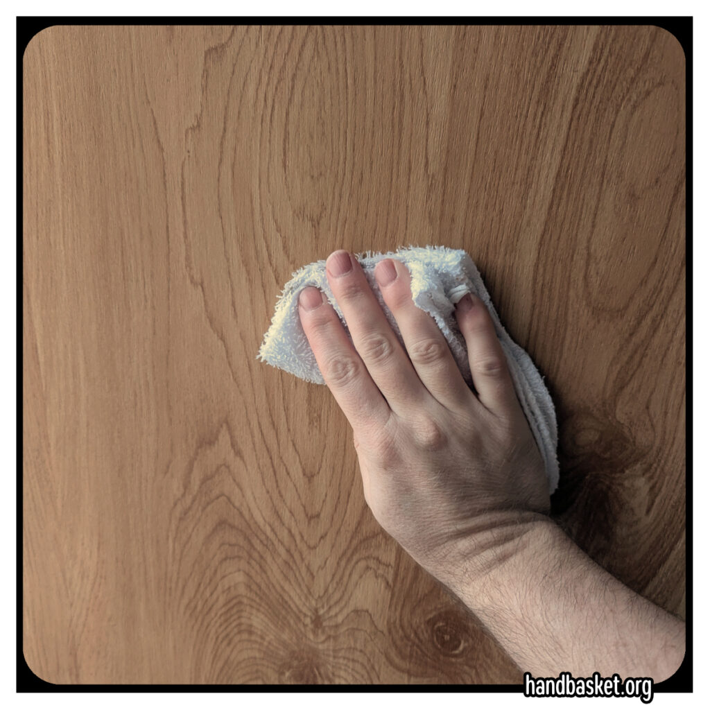my hand wiping a rag across a faux-wood door