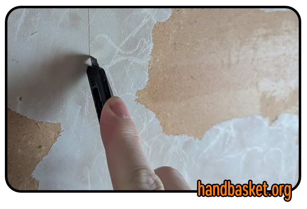 close-up of a box cutter slicing into wallpaper